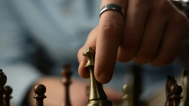 A hand moving a chess piece on a board